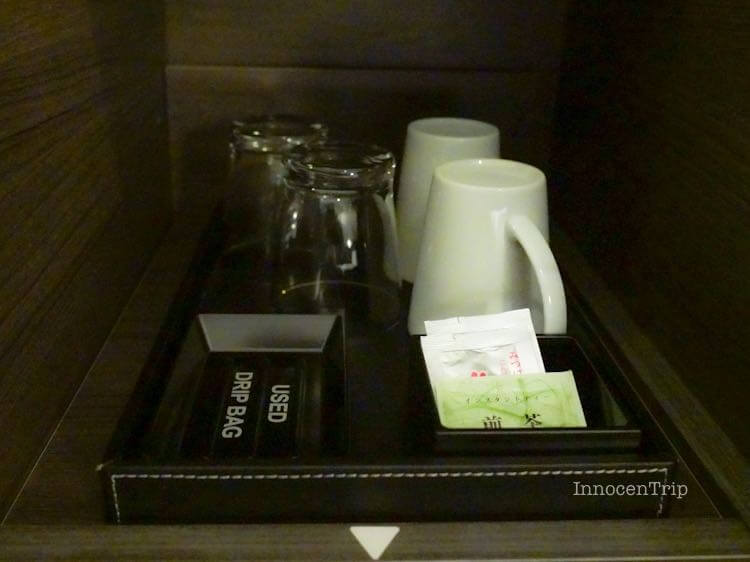 マグカップと粉末茶が並ぶ客室のティーセット